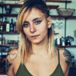 Close-up portrait of a tattooed young woman with blonde hair indoors, exuding confidence and style. and Close-up portrait of a tattooed young woman with blonde hair indoors, exuding confidence and style.