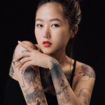 Portrait of a tattooed woman with red lips posing in a studio. and Portrait of a tattooed woman with red lips posing in a studio.